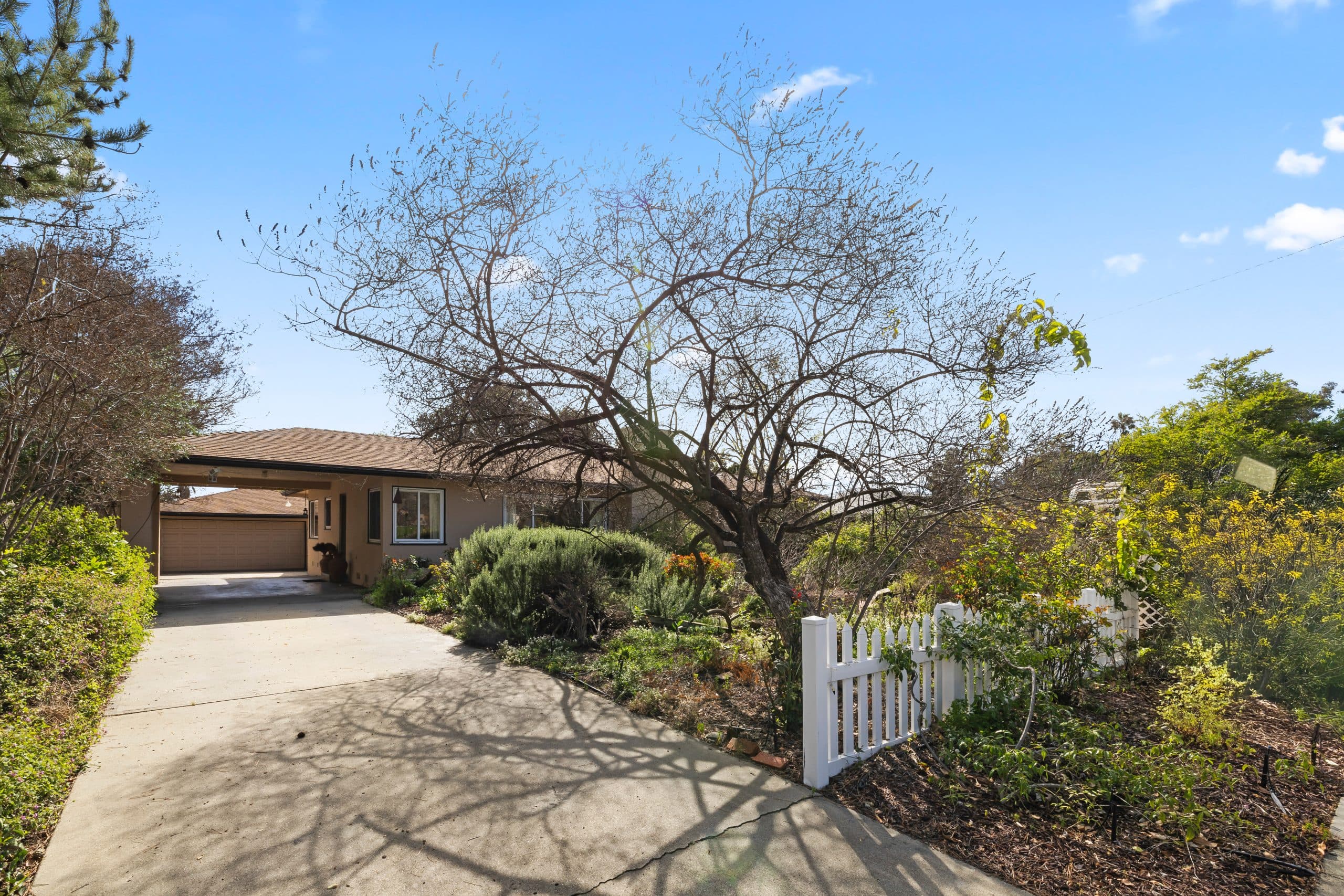 Claremont family home with a white picket fence, long driveway, and cottage garden landscaping